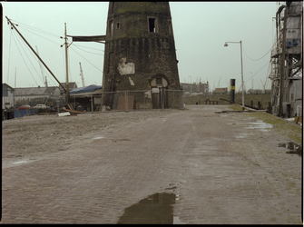 72798 Zicht op de molenstomp van molen de Distileerketel. Rechts de Voorhaven met een elevator, daarachter de Middenkous.