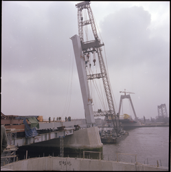 74875 Zicht op de montage van brugdelen tijdens de bouw van de Willemsbrug vanaf het Bolwerk. Op de achtergrond rechts ...