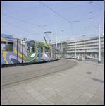 77476 Zicht op het Stationsplein met op de achtergrond het Centraal Station en op de voorgrond een aankomende tram.