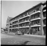 8158 Woningen aan de Prins Hendrikkade met bewoners op de balkons en op straat.