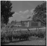 8452 Leerlingen spelen op een grasveld voor een noodschoolgebouw aan de Rollostraat.