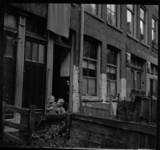 AO-138 Woningen aan de Hendrikstraat, ter hoogte van huisnummer 102. Links vooraan zit een jongen met een jonger familielid.