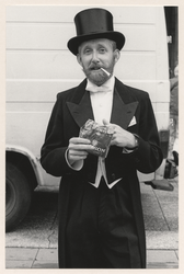 1987-826 Man in kostuum en met hoge hoed rookt shag. Uit een serie van 10 foto's over de Kunstmarkt op de Coolsingel.