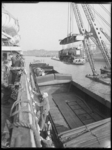 L-1152 In de Maashaven plaatst een drijvende kraan een locomotief in het ruim van een schip. De kraan wordt begeleid ...