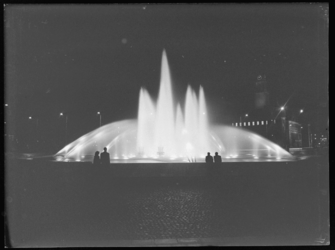L-1276 Silhouetten van toeschouwers steken af tegen verlichte fonteinen op het Hofplein. Rechts op de achtergrond het ...