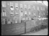 L-1517 Bouwvallige woningen aan het hofje aan de Boomgaardsstraat. Op de voorgrond staan fietsen tegen een hek met ...