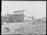 L-1823 Het gebouw van Twaalf Provinciën (Flevogebouw) aan de Hoogstraat. Rechts braakliggende grond, links op de ...