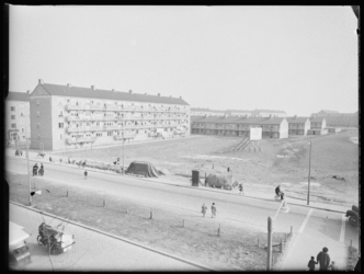 L-1860 Flatgebouwen en duplexwoningen bij de Slinge in Zuidwijk. Kinderen spelen bij een opgebroken trottoir. Links ...