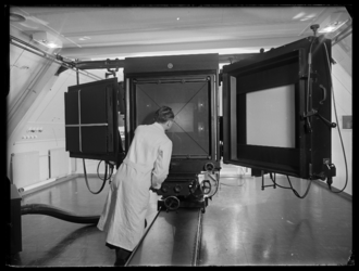 L-1879 Fotograaf stelt reproductiecamera scherp op een te fotograferen document. Uit een serie over de Fototechnische ...