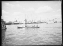 L-1914 Een motorboot van de GEM met een groepje passagiers (mogelijk havenarbeiders) passeert in de Maashaven. Op de ...