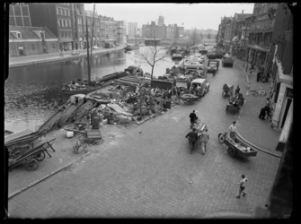 L-1958 Mannen laden en lossen schroot met handkarren en fietskarren bij de schrootopslag op de Rechter Rottekade. Links ...