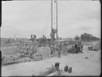 L-2025 Bouwvakkers storten beton bij de bouw van het Nationaal Koopvaardijmonument De Boeg. Op de achtergrond de Leuvehaven.