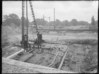 L-2079 Bij de Van Aerssenlaan slaat een heimachine palen tijdens de bouw van de Diergaardetunnel onder het spoor door. ...