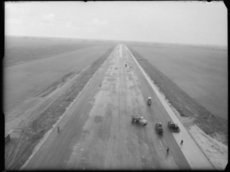L-2099 Luchtfoto van het asfalteren van een baan voor vliegveld Zestienhoven. Op de voorgrond een asfalteringsmachine ...