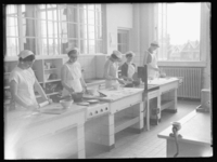 L-2129 Leerlingen tijdens kookles in de nijverheidsschool aan de Catharina Beersmansstraat.