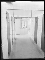 L-215 Gang met bad- en toiletruimtes. Op de achtergrond de portiersloge. Uit een serie over het badhuis in de ...