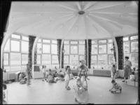L-2810 Docent (rechts) met leerlingen in een speelruimte van de kleuterschool aan de Ameidestraat.