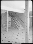 L-3074 Hal en trappenhuis van een school aan de Larikslaan met betegelde vloer en zuilen met keramiek.
