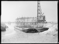 L-319 Op twee pontons bouwen mannen aan een steiger. Rechts staat een heimachine. Uit een serie over de bouw van de ...
