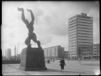L-3303 Een vrouw loopt langs het standbeeld 'De verwoeste stad' van kunstenaar Ossip Zadkine op Plein 1940. Rechts de ...