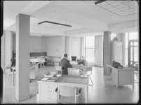 L-3387 Een medewerker zit aan een bureau van een kantoor. In de ruimte staan meerdere bureaus. Uit een serie over ...