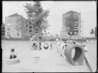 L-3651 Kinderen spelen op een speelplaats aan de Bakoestraat. Op de achtergrond woonblokken.