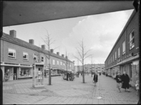 L-3854 Mensen winkelen op binnenplaats Zijpe in Pendrecht. Aan weerszijden winkels met bovenwoningen, links op de ...