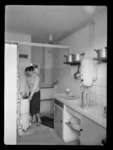 L-4182 Interieur van een woning aan de Karbouwstraat in Kralingseveer. Een vrouw bij de wasmachine het washok met lavet ...
