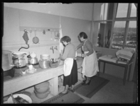 L-52 In de keuken van Openluchtschool Oud-Mathenesse aan de Laanslootseweg doen twee vrouwen de afwas. De vrouw links ...