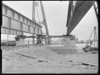 L-547 Met een drijvende kraan plaatsen bouwvakkers stalen balken voor de Botlekbrug op de rivierpijlers. Op het ...