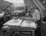 L-6466 Twee mannen bouwen maquettes in een werkruimte van het Stadstimmerhuis aan het Haagseveer. Op de werktafels ...