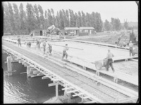 L-816 Bouwvakkers storten beton bij de bouw van de Crooswijksebrug op de Boezembocht. Op de achtergrond staan bouwketen ...