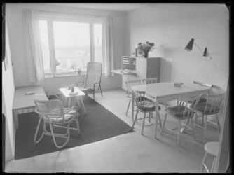 L-896 Eenvoudig ingerichte woonkamer van een woning aan Schuilenburg, met zithoek, eettafel en opbergkast.
