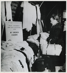1968-311 Vrouw zoekt tussen goederen en kleding die zijn geschonken door het Curaçaosch Steuncomité.