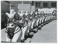 1970-2628 Een rij kermispaardjes op wielen staat klaar bij de Hugo de Grootstraat op het terrein van de voormalige ...