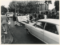 1977-2584 Moeders met een spandoek en stopborden demonstreren voor de verbetering van de verkeersveiligheid op het kruispunt.