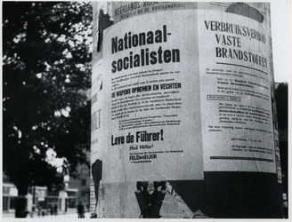 1977-3113 Reclamezuil waarop Duitse aanplakbiljetten met propaganda en aankondigingen in verband met de ...