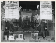 1977-3192 Een etalage van een zuivelhandel met aankondigingen van het beschikbaar stellen door het Rode Kruis van ...
