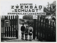 1977-3206 Drie jongens staan met hun opgerolde handdoek bij het hek van Stichting Zwembad Schuagt te Krimpen aan de Lek ...