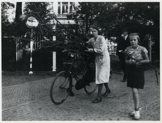 1977-3207 Een vrouw vervoert sprokkelhout met de fiets, vanwege de brandstofschaarste tijdens de Hongerwinter en de ...
