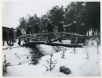 1977-3371 Arbeiders in het gelid over een houten brug in een werkkamp, georganiseerd door de Nederlandsche ...