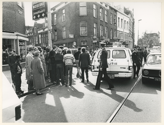 1979-2097 Belangstellenden uit de buurt en politieagenten bij een politieauto.