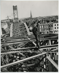 1981-1165 Een Duitse militair poseert op de bovenste binten van de spoorbrug over de Nieuwe Maas. Op de achtergrond: de ...