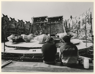 1990-636 Twee kermisexploitanten rusten uit bij het opbouwen van hun attractie op de Rivoli-kermis.