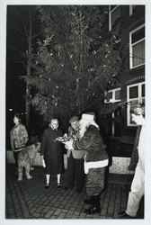 1993-3678 Opzoomeren. Bewoners van de Opzoomerstraat presenteren chocolademelk en oliebollen bij de kerstboom, die ze ...