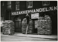 XXXIII-497 De NV zakkenhandel van het K. Hulst aan de Eenhoornstraat 6b laat met een barricade van zandzakken zien hoe ...