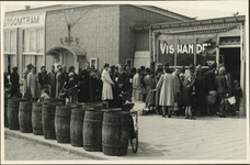 XXXIII-658 Rotterdammers staan in de rij voor een vishandel, waar de eerste Zweedse haring aan de bevolking wordt uitgedeeld.
