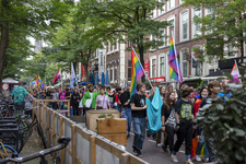 46-82 Pride March Rotterdam tijdens Rotterdam Pride 2021. Betogers met regenboogvlaggen wandelen door de Witte de Withstraat.