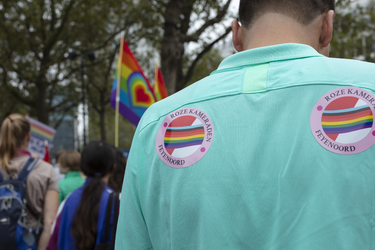 46-9 Pride March Rotterdam tijdens Rotterdam Pride 2021. Betogers met regenboogvlaggen en iemand met stickers van de ...