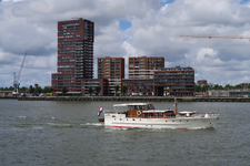 486 Een pleziervaartuig op de Nieuwe Maas met op de achtergrond appartementencomplexen aan de Lloydkade.